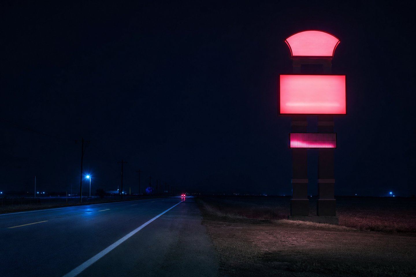 A tall illuminated casino pylon sign standing beside an empty two-lane highway at night, with flat open country either side and a single pair of distant taillights.